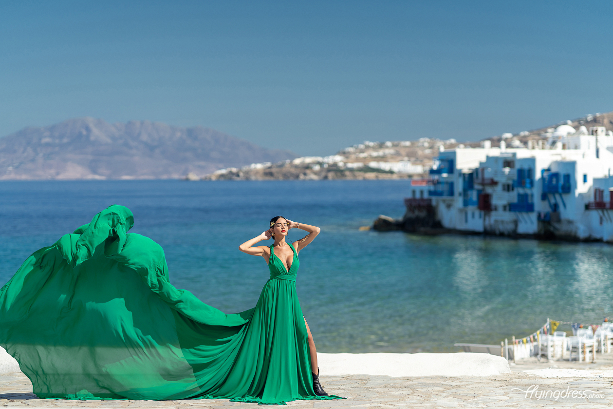 Create unforgettable memories in Mykonos with a flying dress photoshoot, where the vibrant green gown adds a stunning contrast to the blue sea and picturesque Little Venice.